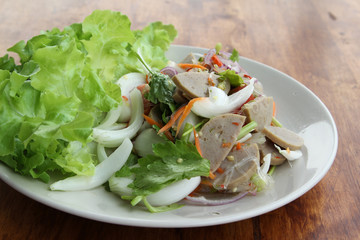 Thai cuisine spicy pork salad on white plate.
