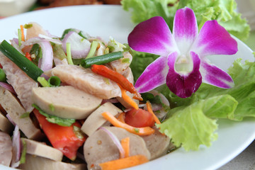 Thai cuisine spicy pork salad on white plate.