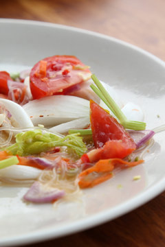 Thai cuisine spicy pork salad on white plate.