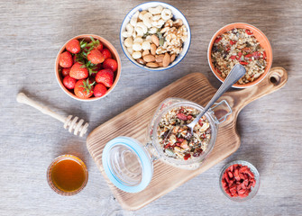 Grain free oat free paleo muesli, raw food: mixed nuts, seeds, goji berries, chia, honey and strawberries, selective focus