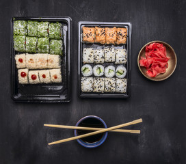 Japanese fast food, sushi set with various ingredients in plastic containers on a dark rustic background, top view