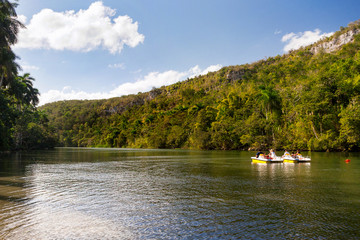Obraz premium Tourists on catamarans float down the river between wooded mountains. Cuba.