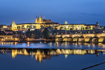 Night view over river Vltava and Charles bridge to Prague castle with copy space in clear sky