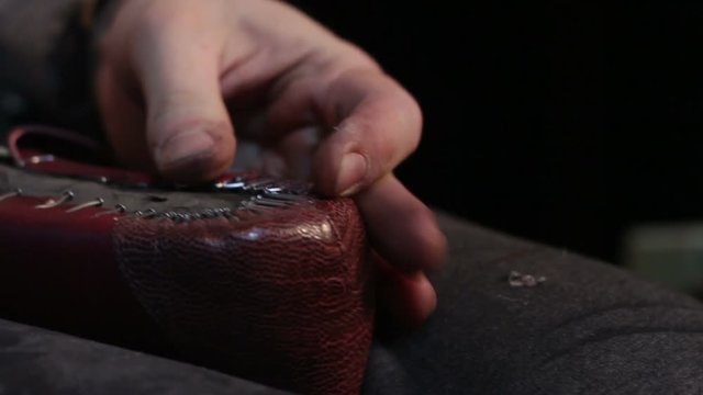 Shoemaker sews shoes. Hammering shoe leather