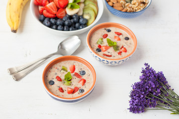 Vegan fruit and berry smoothie breakfast, topped with blueberries, strawberries and mint, seved with fruits, berries and nuts, selective focus