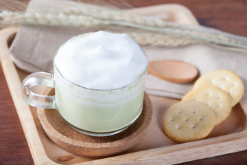 close up hot green milk with biscuits on wooden plate on wooden