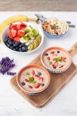 Fototapeta na wymiar Vegan fruit and berry smoothie breakfast, topped with blueberries, strawberries and mint, seved with fruits, berries and nuts, selective focus