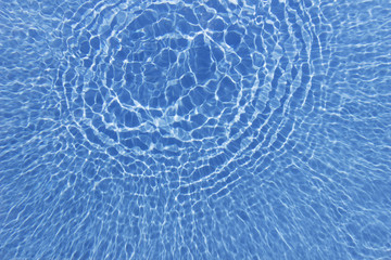 Swimming pool with sunny reflections. Texture of the water.