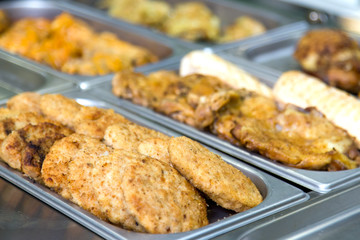 Meatballs and meat dishes at the buffet on metal plates.