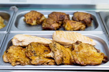 Fried chicken pieces at the buffet on metal plates.
