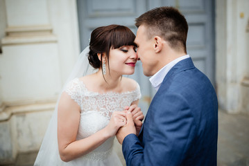Bride and groom at wedding Day walking Outdoors near architecture. Bridal couple, Newlywed woman and man embracing with love