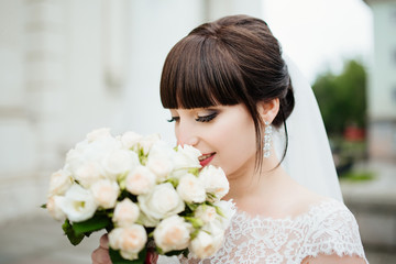 Naklejka premium Beautiful smiling bride portrait near architecture with flowers