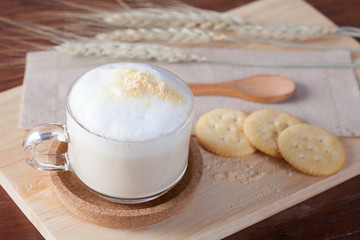 Hot milk with biscuits on wooden plate on wooden table for break