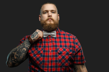 Fototapeta premium Tattooed bearded unformal male in red shirt and grey bow tie.