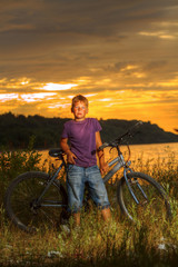 boy on a bicycle near the sea in the evening at sunset