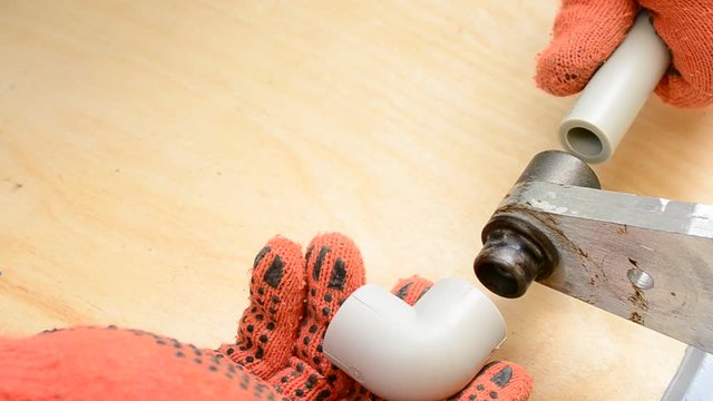 Hands in gloves soldering plastic pipes