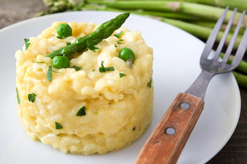 Risotto with asparagus, parsley and peas on a rustic wooden table

