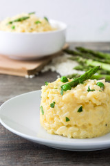 Risotto with asparagus, parsley and peas on a rustic wooden table

