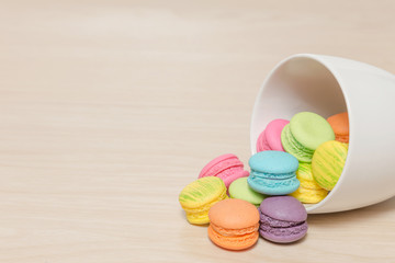 Pile of colorful macaroons cookies in cup on wooden with copy sp