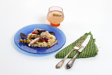 Traditional italian risotto with chicken, tomato, basil and parmesan on blue plate with knife and fork and glass of wine