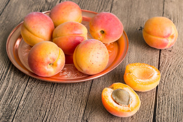 Naklejka na ściany i meble Ripe juicy apricots. Ripe juicy apricots on a round copper tray on a wooden table.