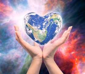 World in heart shape with over women human hands on blurred natu