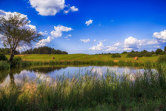 Fototapeta haystacks on the field with a pond in Poland