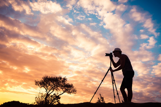 The art of photography. Male photographer taking photos of a beautiful sunset. 