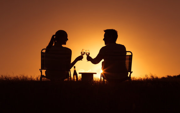 Couple relaxing in the park enjoying a glass of wine. 