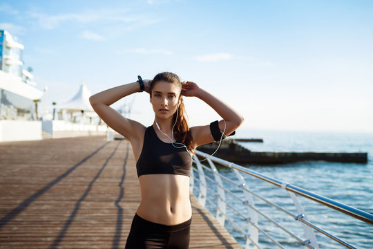 Picture of young attractive fitness girl with sea coast on background