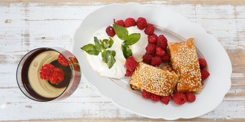 Piece of traditional apple strudel pie served with ice-cream, fresh mint, raspberry and glass of...