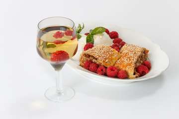 Piece of traditional apple strudel pie served with ice-cream, fresh mint, raspberry and glass of wine