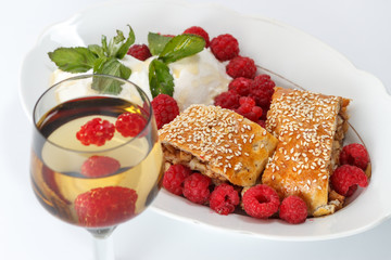 Piece of traditional apple strudel pie served with ice-cream, fresh mint, raspberry and glass of wine