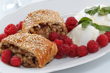 Piece of traditional apple strudel pie served with ice-cream, fresh mint, raspberry and glass of wine