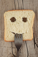 Happy toast with a fork in her mouth on a wooden