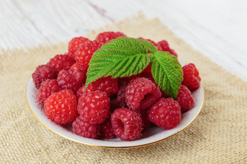 Raspberries in a bowl on a wooden white table
