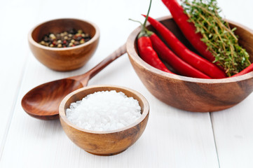 Salt, pepper, chili and thyme in bowls on white rustic wooden table