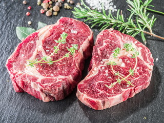 Rib eye steaks with spices on the black background.