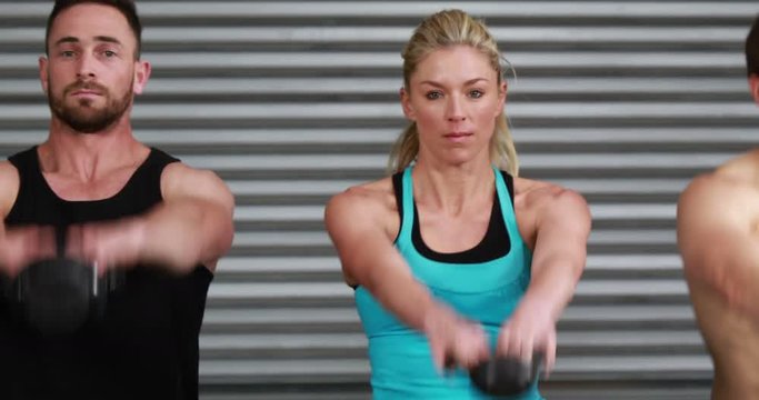 Fit people swinging kettlebell weights at the gym