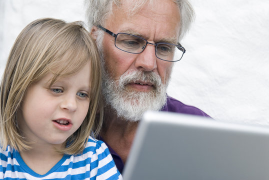 Sweden, Ostergotland, Man with his granddaughter (4-5) using laptop