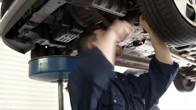 Handsome mechanic reparing a car in his garage