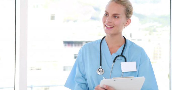 Video of pretty nurse looking at camera and writing on clipboard