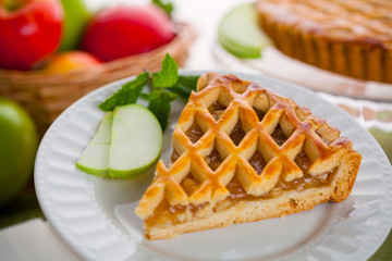 Piece of green apple pie tart dessert served next to basket of fruit