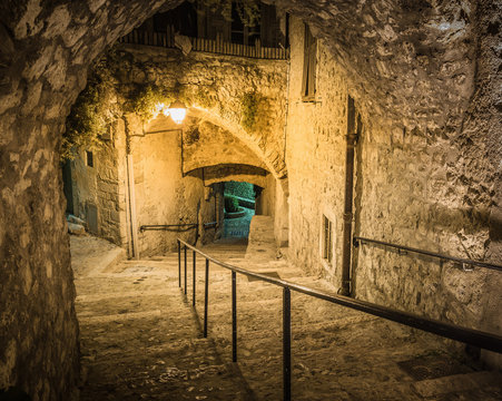 Narrow cobbled street in old town Peille at night, France.