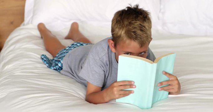 Little boy reading on bed