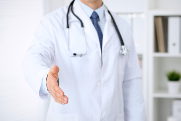Male medicine doctor offering helping hand  for  handshake. Partnership and trust concept.