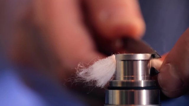 Trim ends of wick from wool of electronic cigarette closeup.