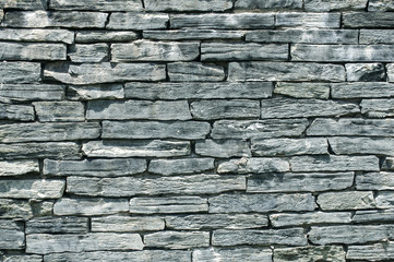 Fence wall made from tiles of gray blue sandstone as background