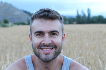 Handsome man smiling in wheat field. Outdoor.