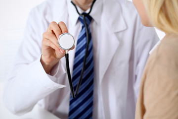 A doctor with a stethoscope in his hand next to his patient . The therapist is ready to examine a patient